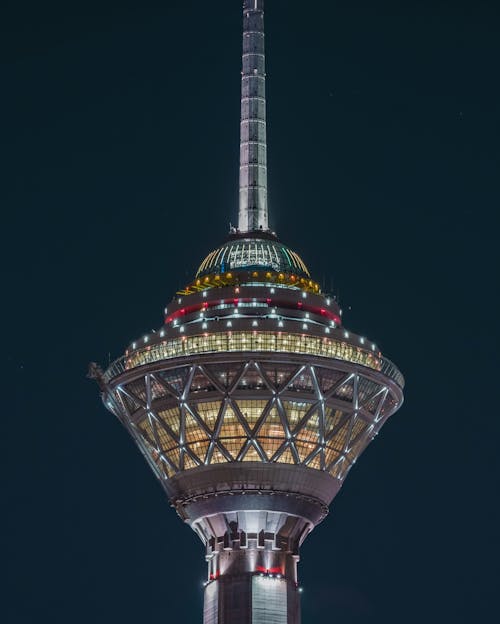 Low angle of high sparkling TV tower with colorful illumination against cloudless dark sky