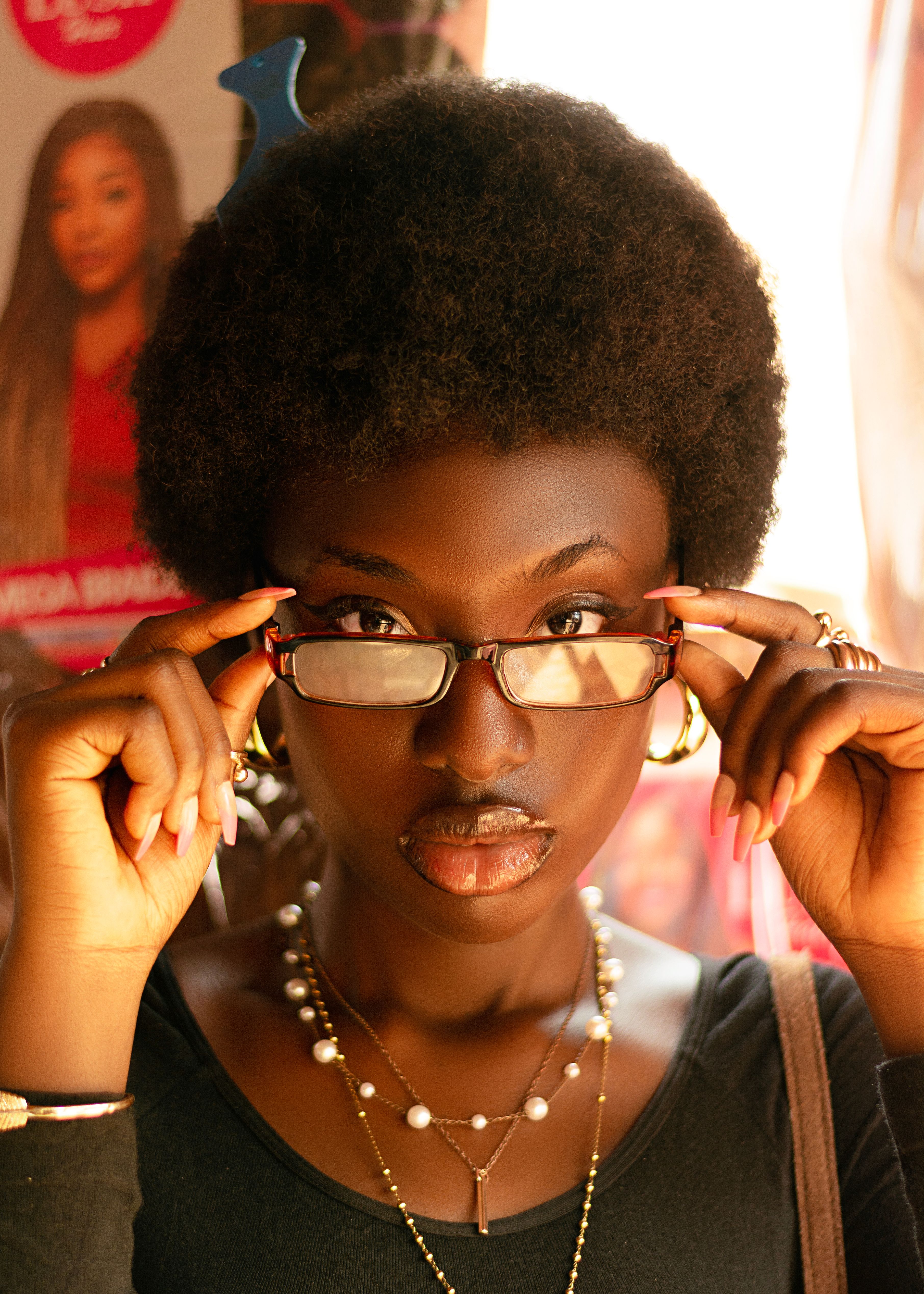 Close-up portrait of a stylish woman adjusting her glasses, showcasing African fashion.