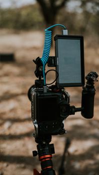 A professional camera with attachments outdoors on a tripod, ideal for filming or photography.
