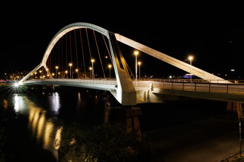 Free Stunning night view of the Puente de la Barqueta bridge reflecting in the river in Sevilla, Spain. Stock Photo