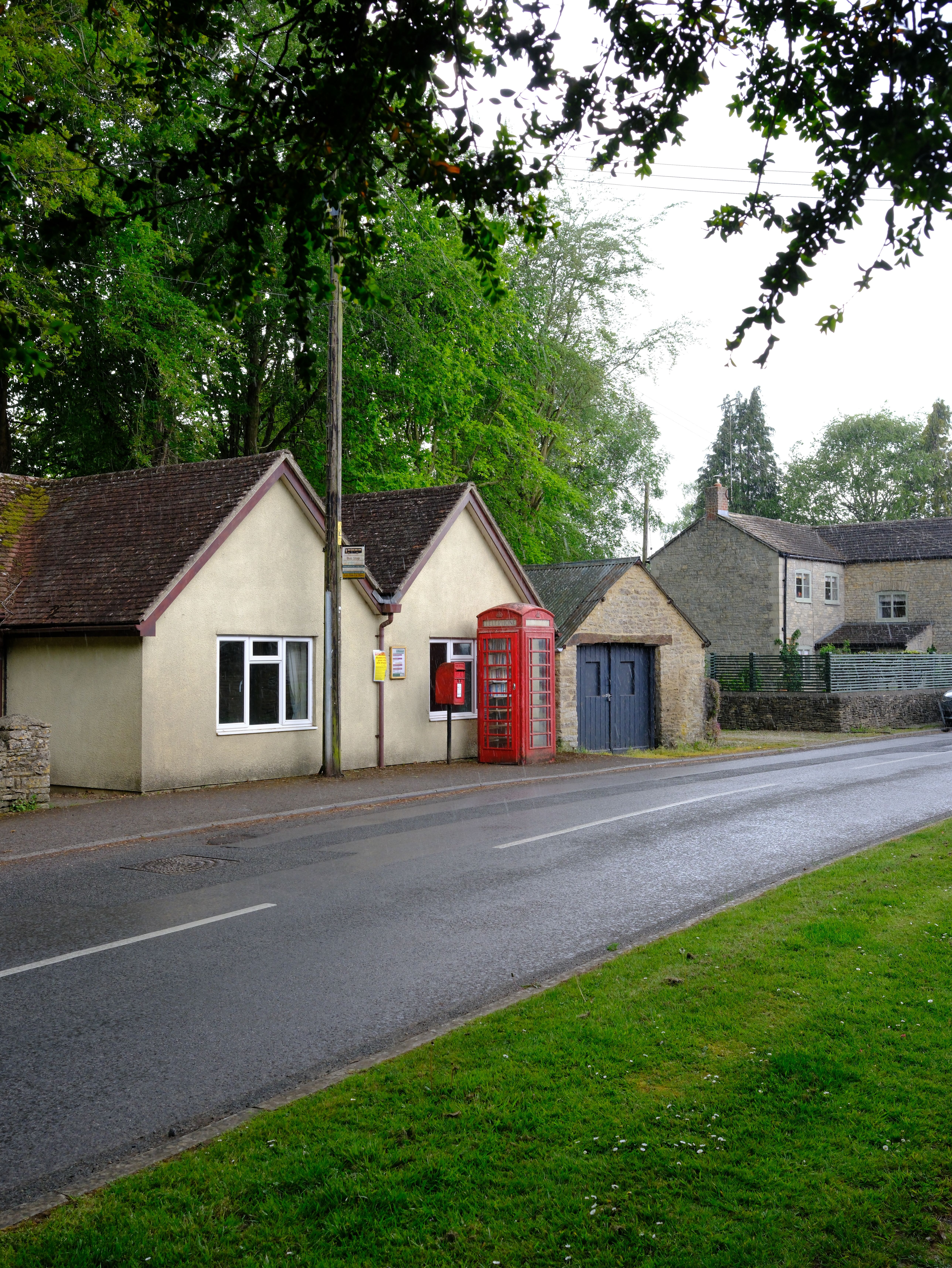 A charming street view in a picturesque English village, featuring a classic red phone box and traditional cottages.