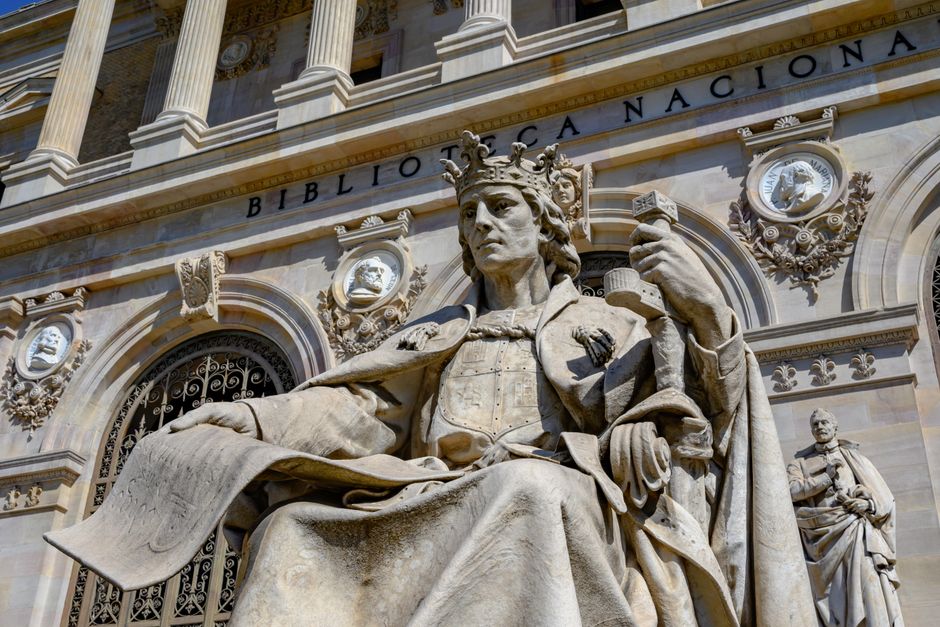 Estatuas de mármol en la majestuosa entrada de la Biblioteca Nacional de Madrid, España, capturadas con vívido detalle.