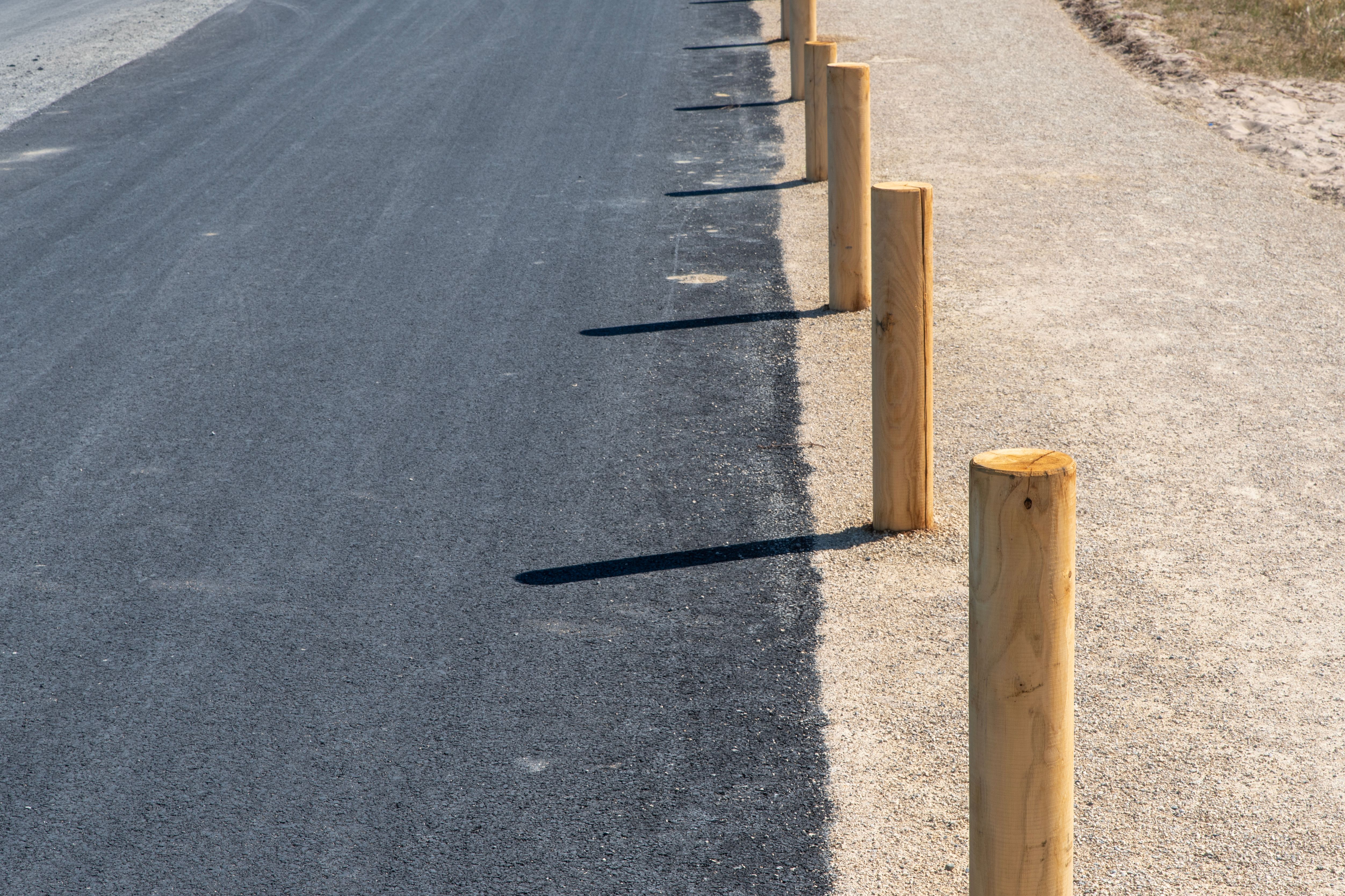 Asphalt Road with Wooden Posts in Sunlight · Free Stock Photo