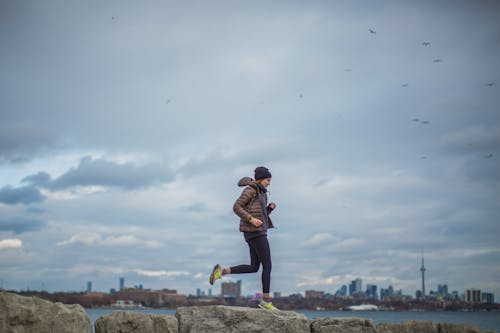 Woman Standing on Stone Near Body of Water