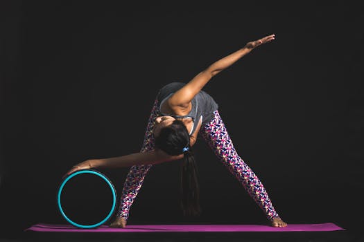 Adult woman performing yoga stretch with a yoga wheel in a studio setting.