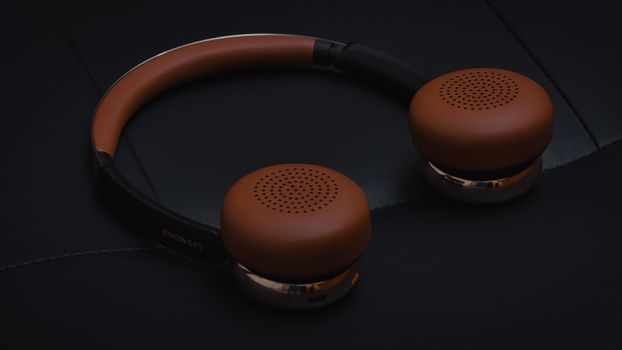 Close-up of stylish brown leather wireless headphones on a black surface, showcasing modern design and elegance.
