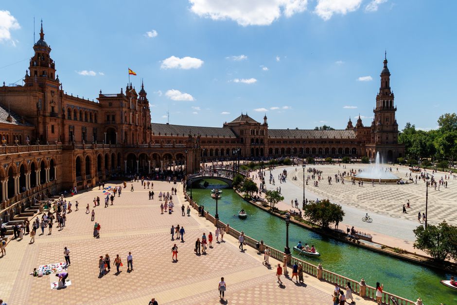 Una escena vibrante de la Plaza de España, Sevilla, que captura la cultura y la arquitectura local bajo un cielo azul.