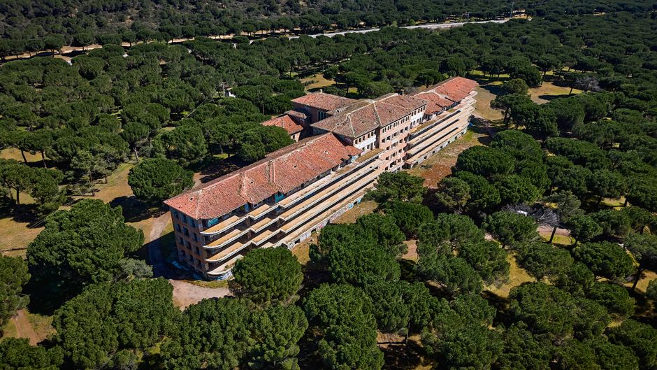Drone capture of an abandoned hospital surrounded by lush pine forest near Valladolid, Spain.