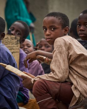 Group of children engaged in outdoor educational activity with focus on one child holding a tablet.