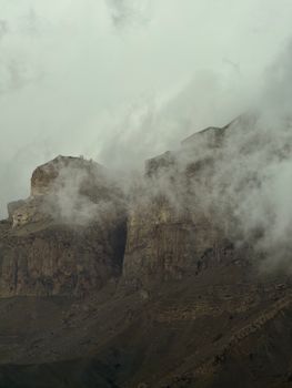 Dramatic view of Caucasus Mountains covered in mist, capturing autumn's moody essence.