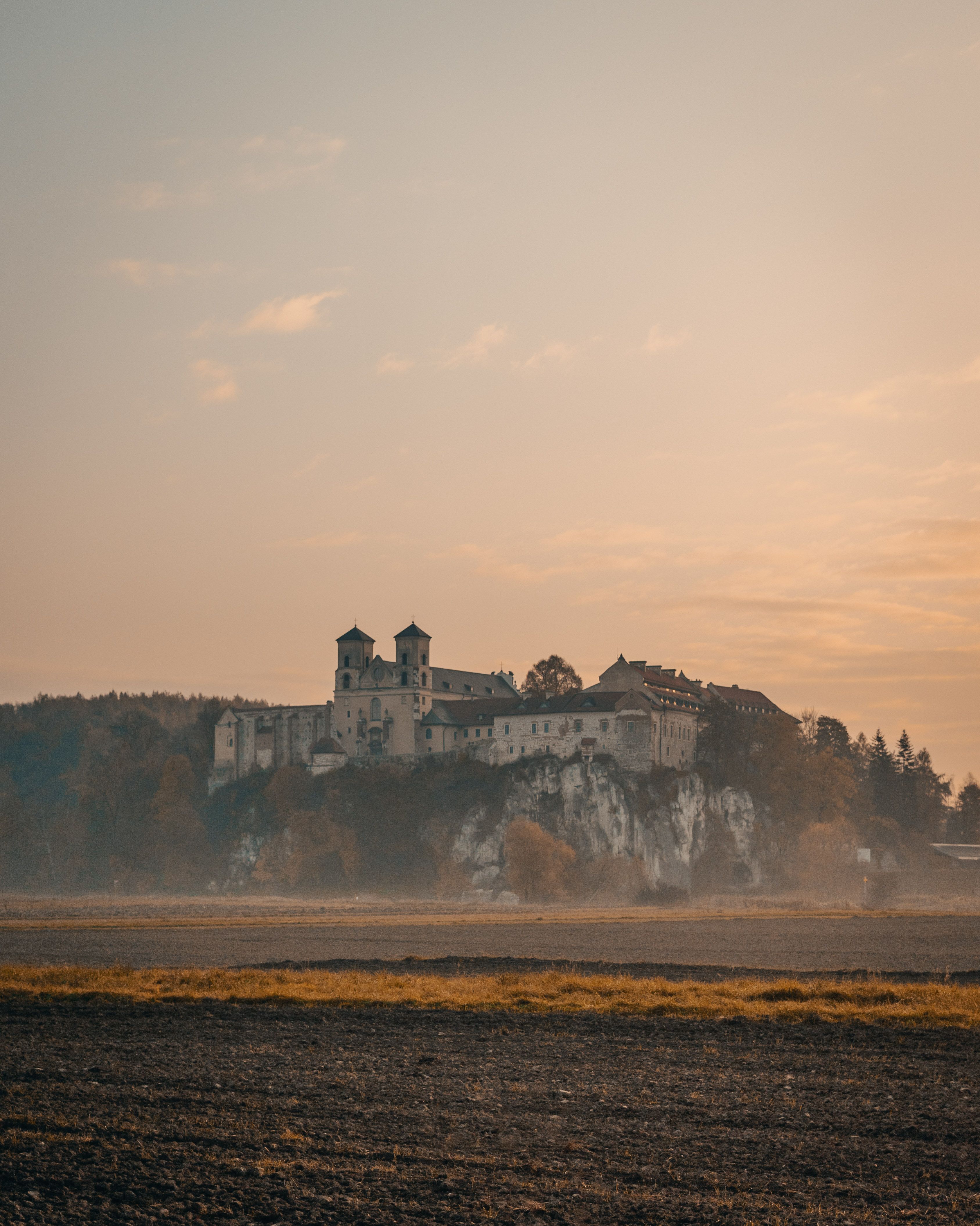 Scenic view of Tyniec Abbey perched on a cliff at sunrise in Kraków, Poland, with a serene morning sky.