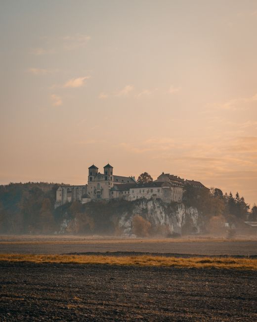 Scenic view of Tyniec Abbey perched on a cliff at sunrise in Kraków, Poland, with a serene morning sky.