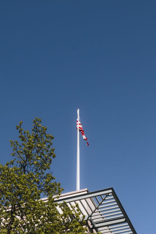 Free Contemporary building with a flagpole under a clear blue sky, captured in Berlin. Stock Photo