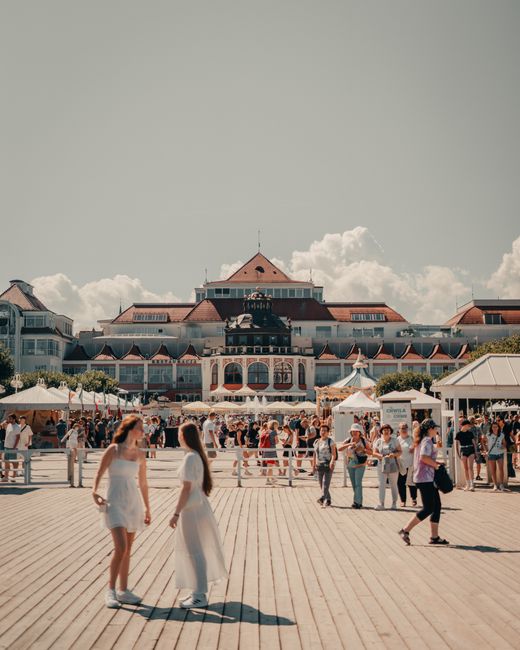 Crowds enjoy a sunny day at Sopot Pier with historical architecture and vibrant atmosphere.