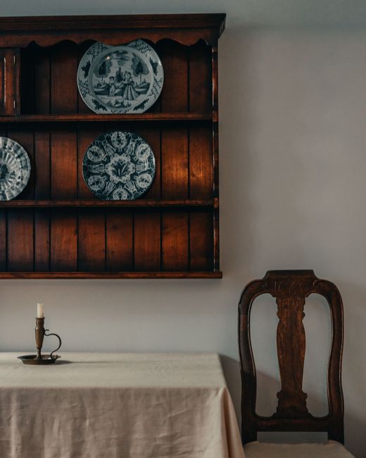 Elegant vintage dining room with a wooden shelf, decorative plates, and a classic wooden chair.