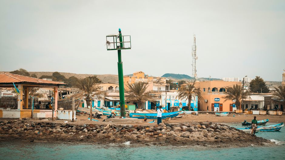 Scenic view of Tadjoura's waterfront with boats and buildings, capturing coastal life in Djibouti.