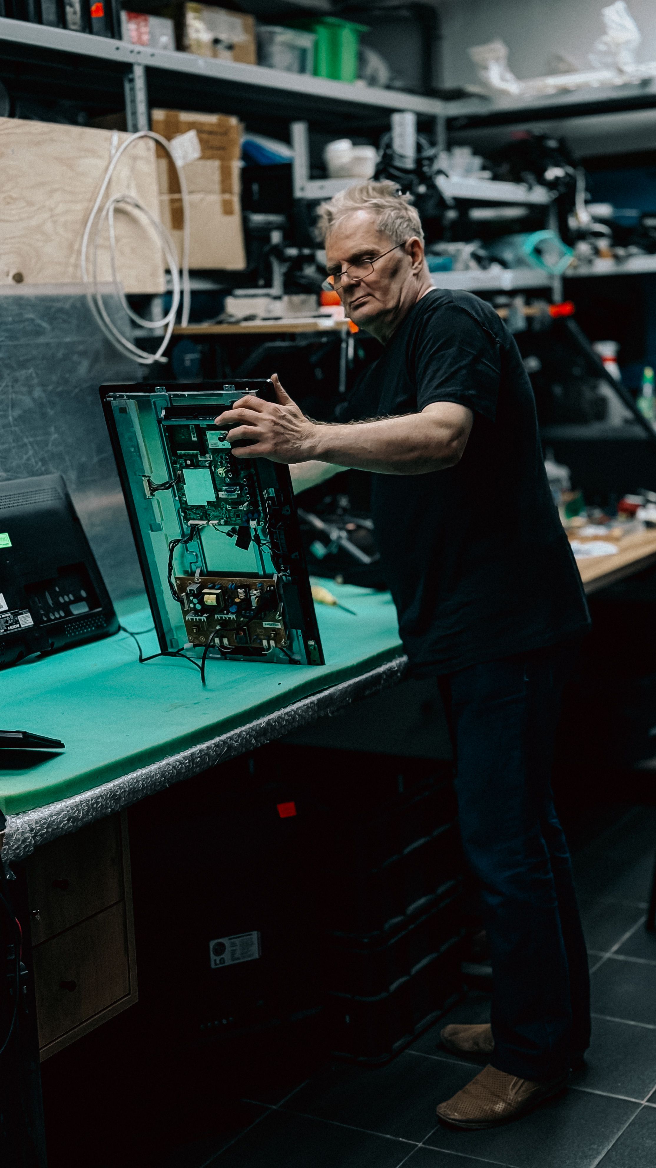 An experienced technician examines a circuit board at a workstation, showcasing technical expertise.