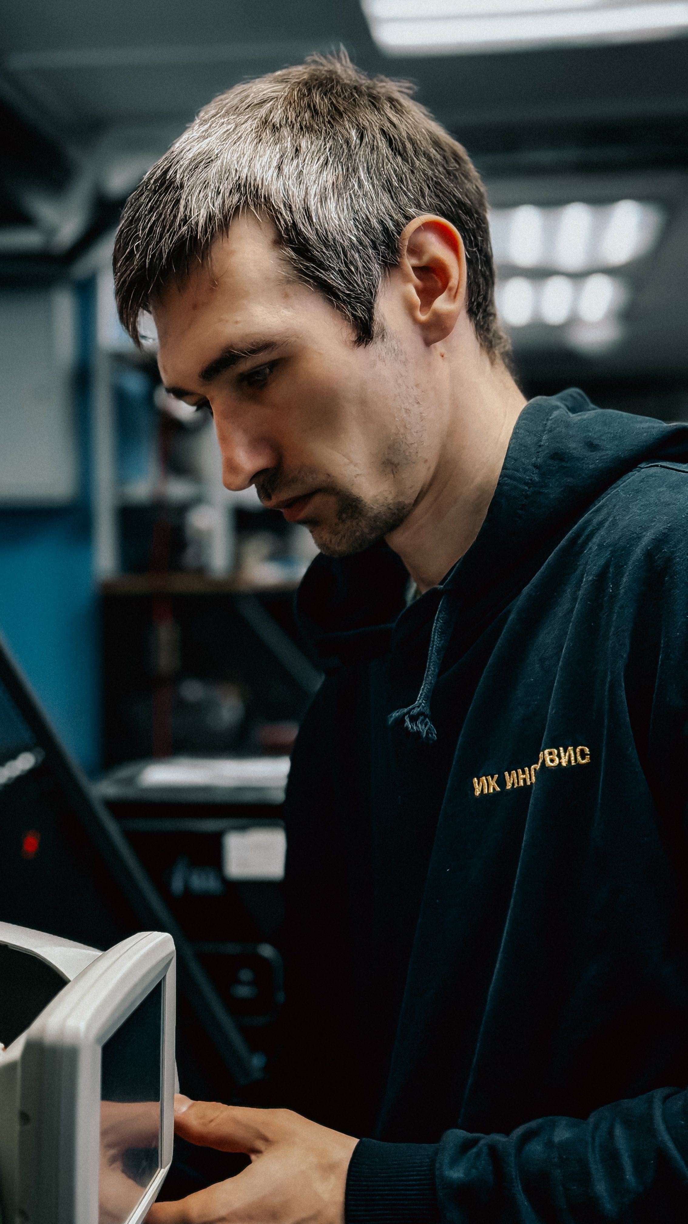 Male technician concentrating on operating advanced machinery in a workshop setting.