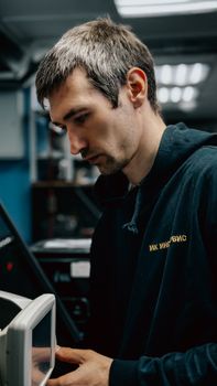 Male technician concentrating on operating advanced machinery in a workshop setting.