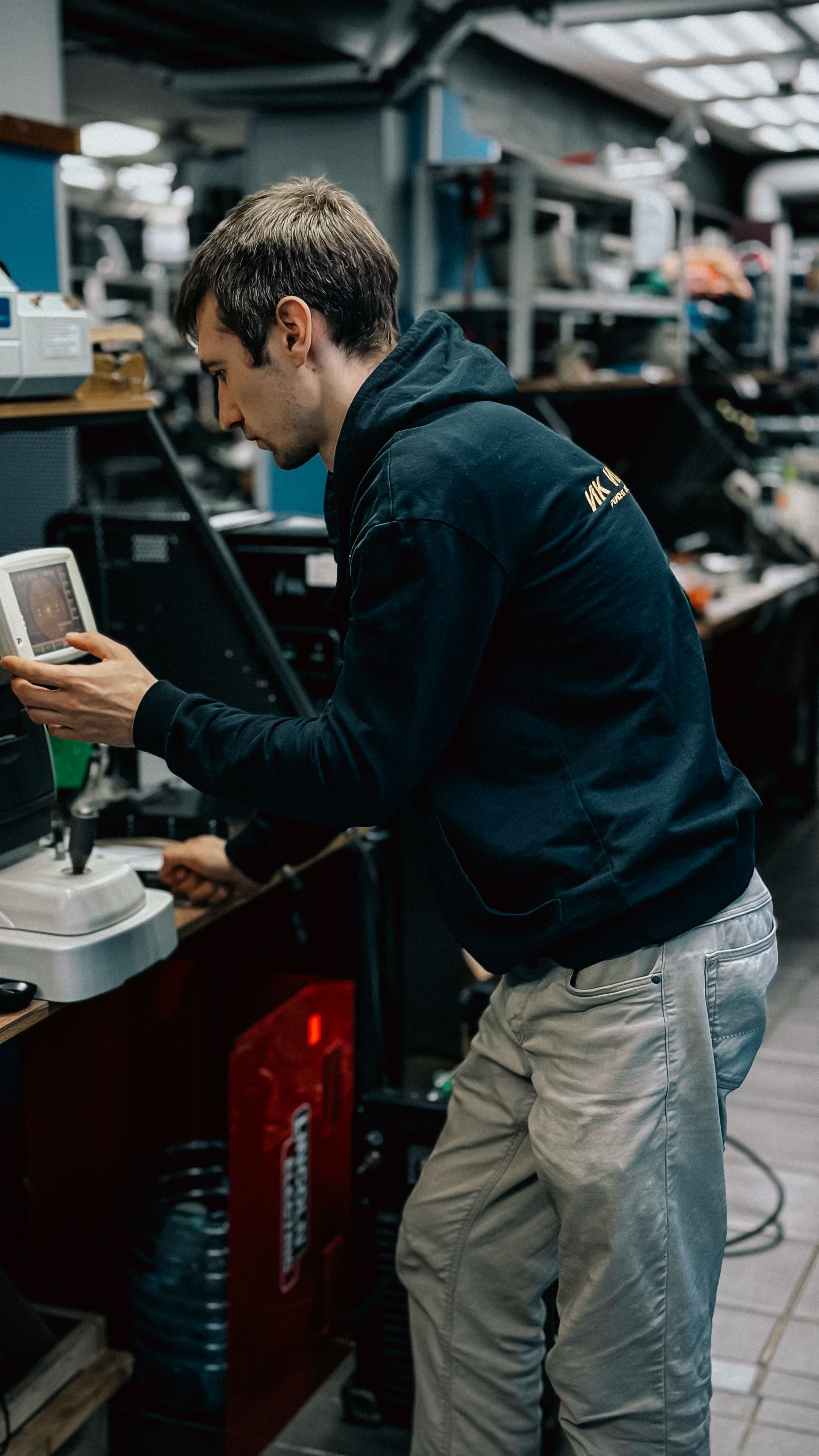 A technician in a workshop adjusts a laboratory device, focusing on precision.