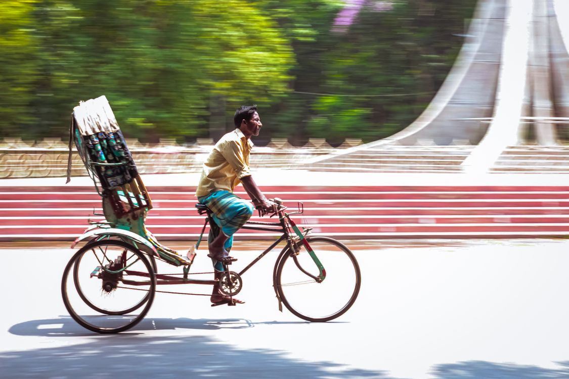 Man Riding Bicycle with Load in Urban Setting · Free Stock Photo
