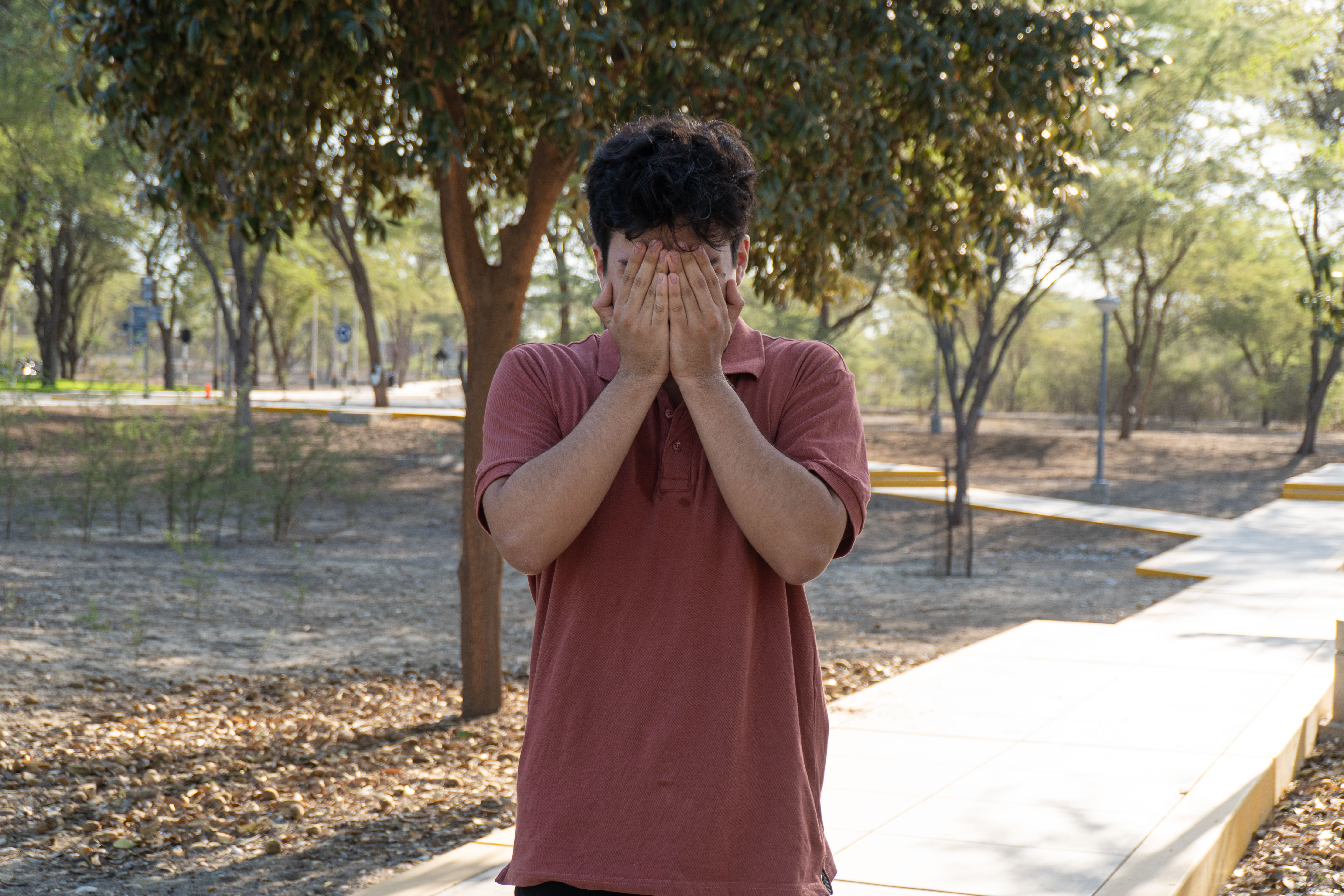 Young Man Covering Face Outdoors in Piura Park · Free Stock Photo