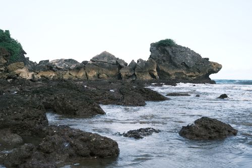 Free Dramatic rocky coastline with unique formations and gentle waves under a clear sky. Stock Photo