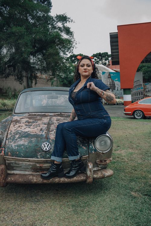 Free A woman in denim poses confidently on a vintage car in an outdoor setting. Stock Photo