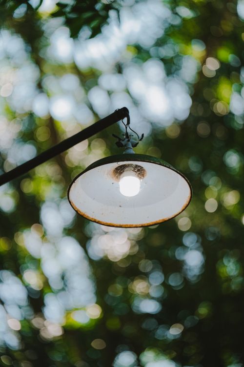 Free Simple outdoor lamp with a rustic design against a blurred green background. Stock Photo