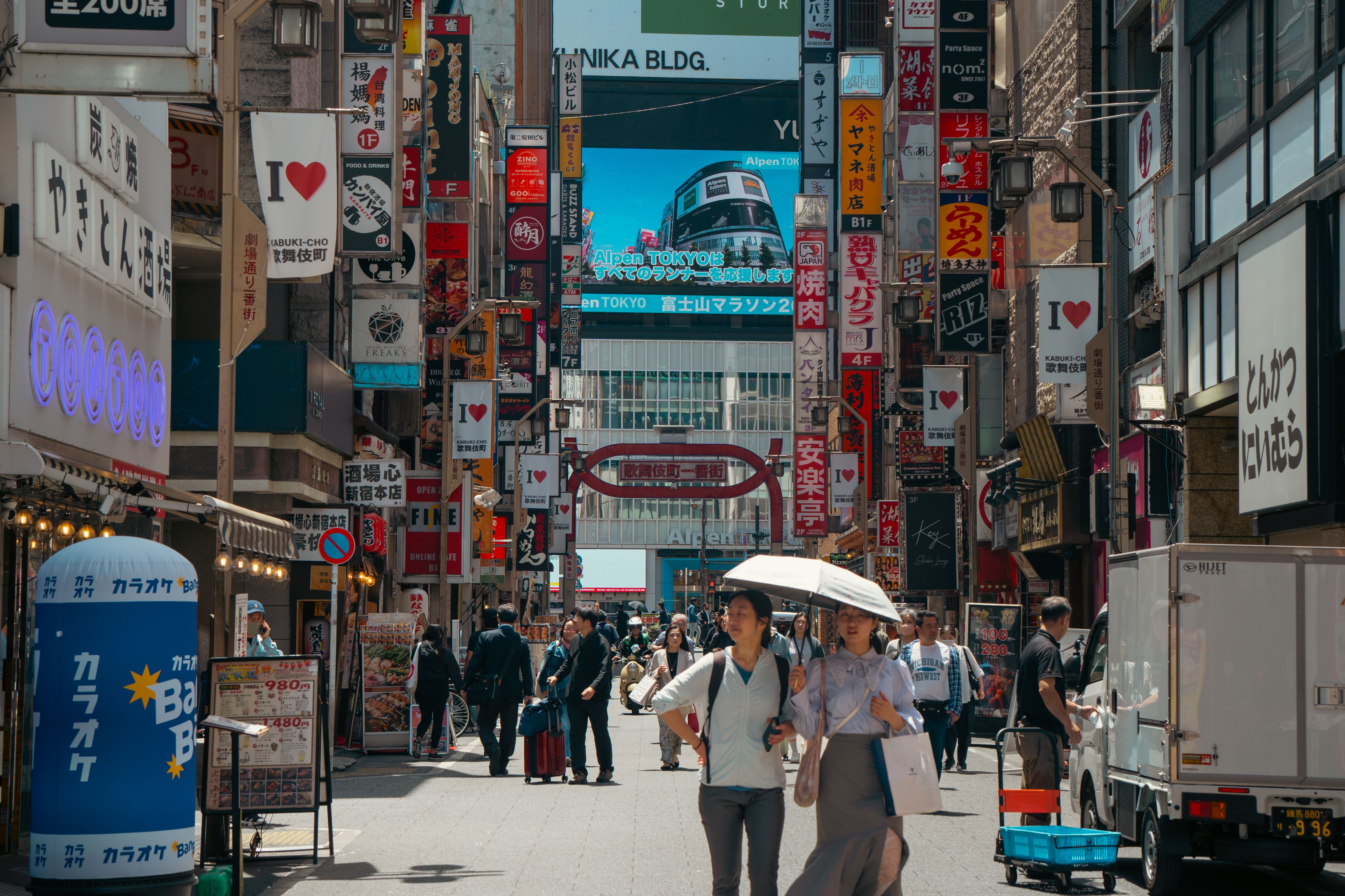 Busy daytime scene in bustling Shibuya, Tokyo with diverse crowd and signage.
