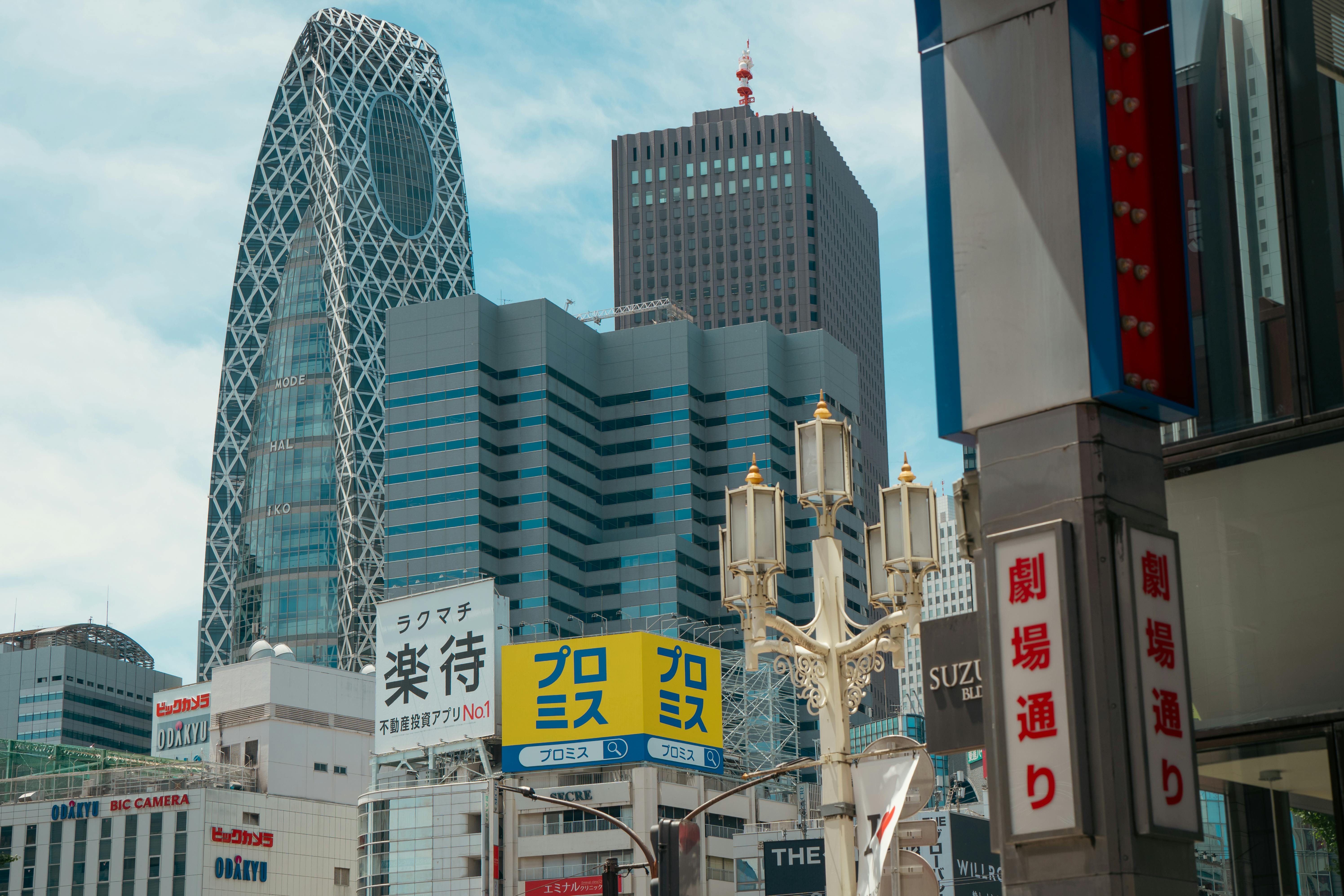 Street view of Tokyo cityscape featuring the iconic Mode Gakuen Cocoon Tower and vibrant urban signage.