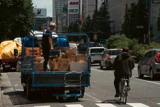 Urban delivery scene in Tokyo featuring a truck and cyclist on a busy street.