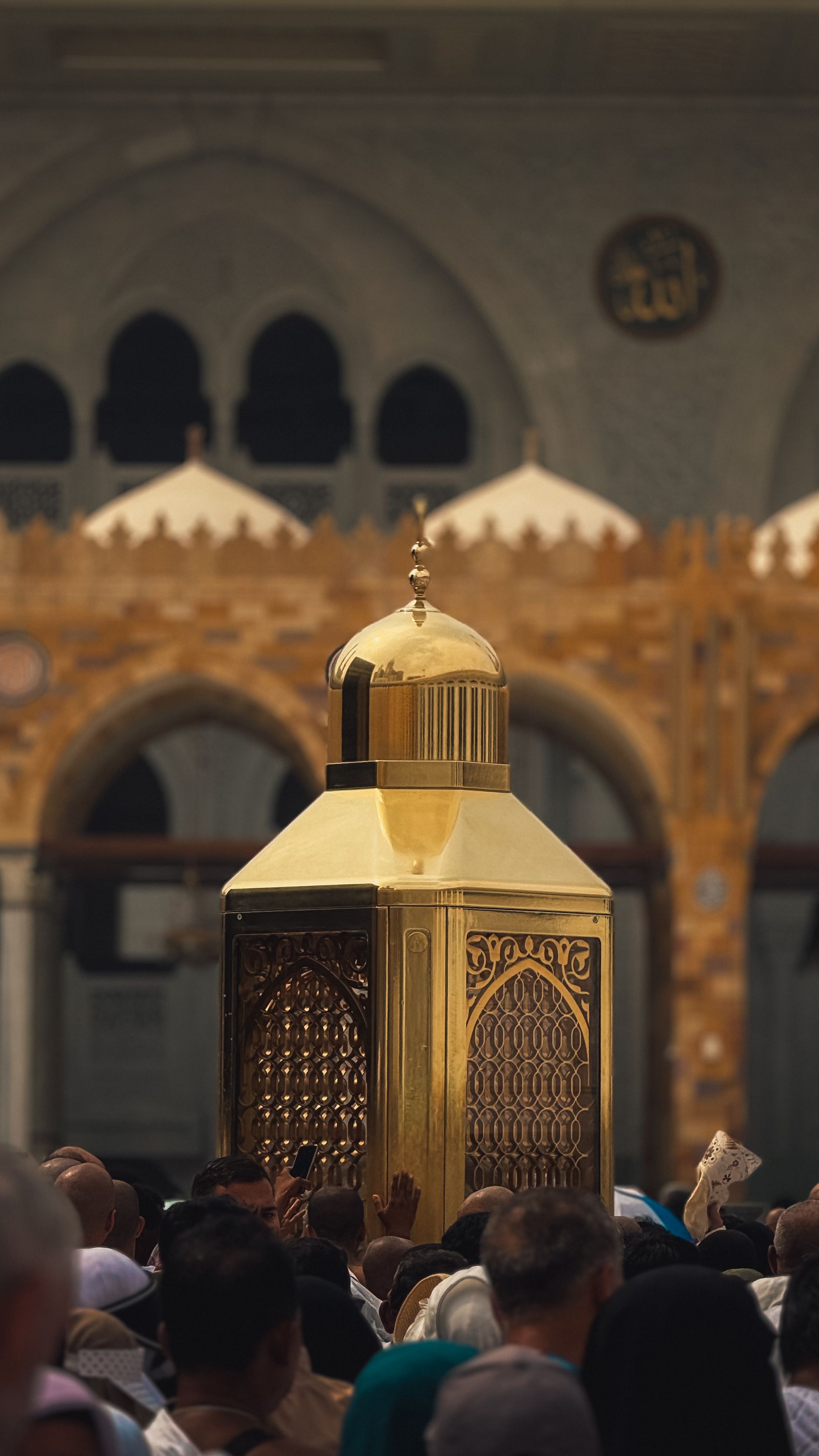 Pilgrims gather around Maqam Ibrahim in Makkah, Saudi Arabia during daylight.