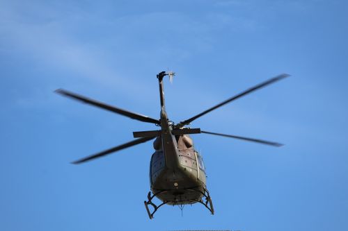 Free A military helicopter flies against a clear blue sky, captured from below. Stock Photo