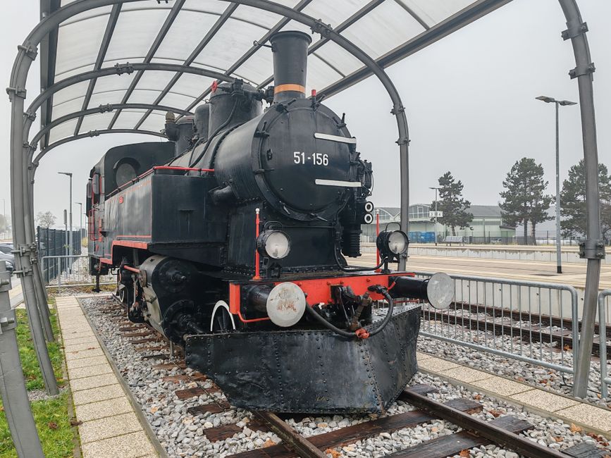 Fotomural Vista frontal de una locomotora de vapor histórica conservada bajo una marquesina moderna.