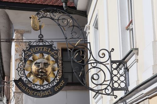 Free Decorative metal hotel sign with sun face design, located on building facade. Stock Photo