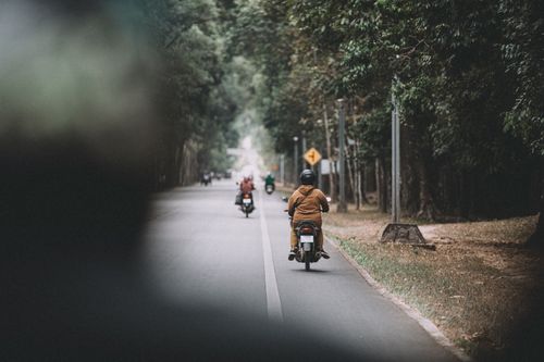 Free Motorcyclists journey through a scenic forest road in Siem Reap, Cambodia, showcasing adventure and exploration. Stock Photo