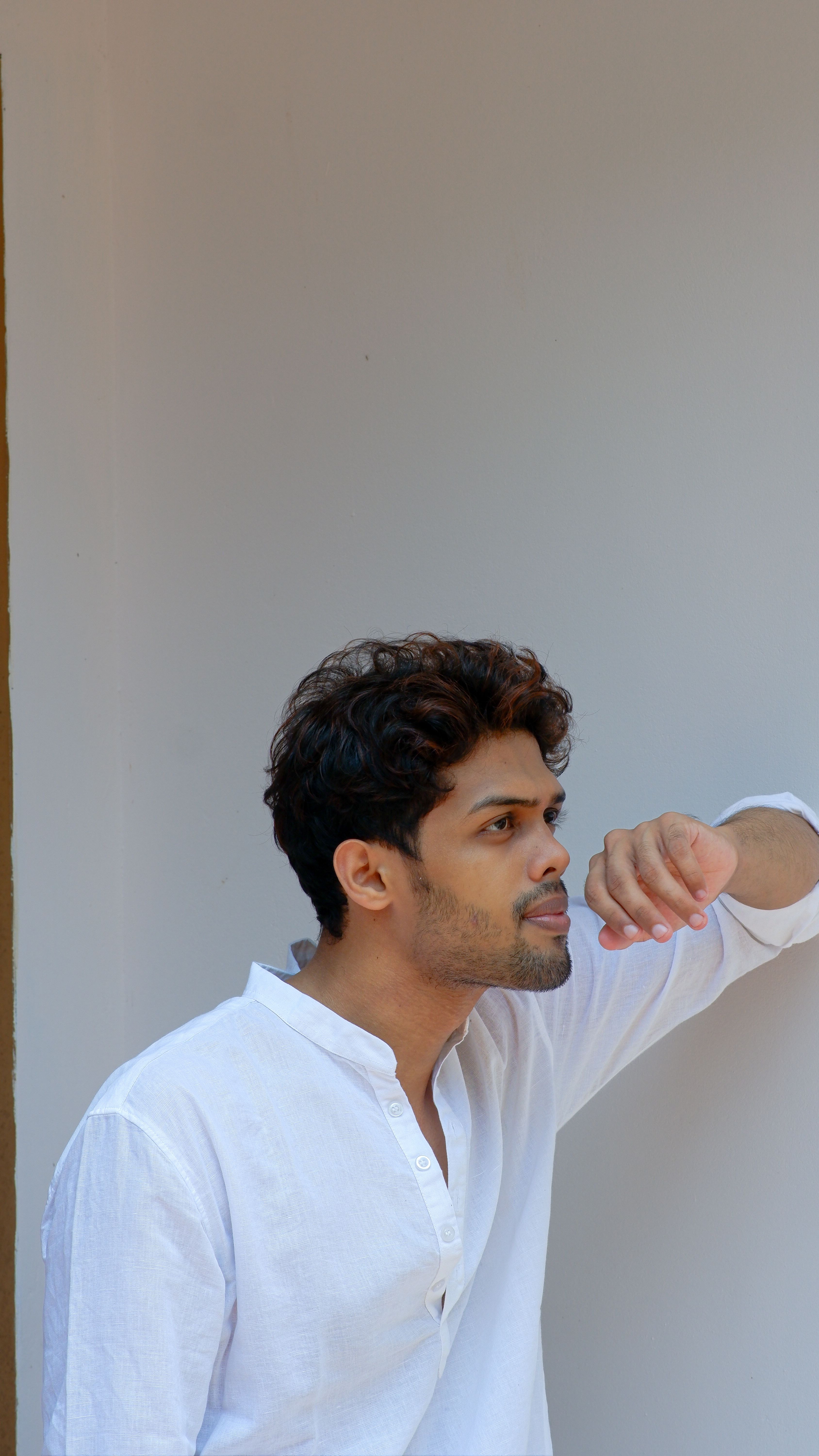 Portrait of a young man in a white shirt looking thoughtfully into the distance.