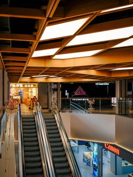 Bright and modern shopping mall interior with escalator and retail stores.