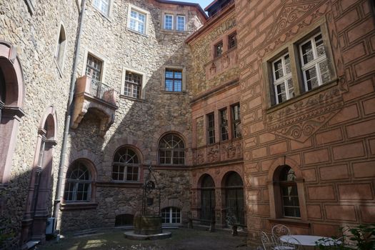 A charming courtyard featuring historical stone walls and arched windows in a European style building.