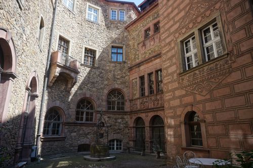 Free A charming courtyard featuring historical stone walls and arched windows in a European style building. Stock Photo
