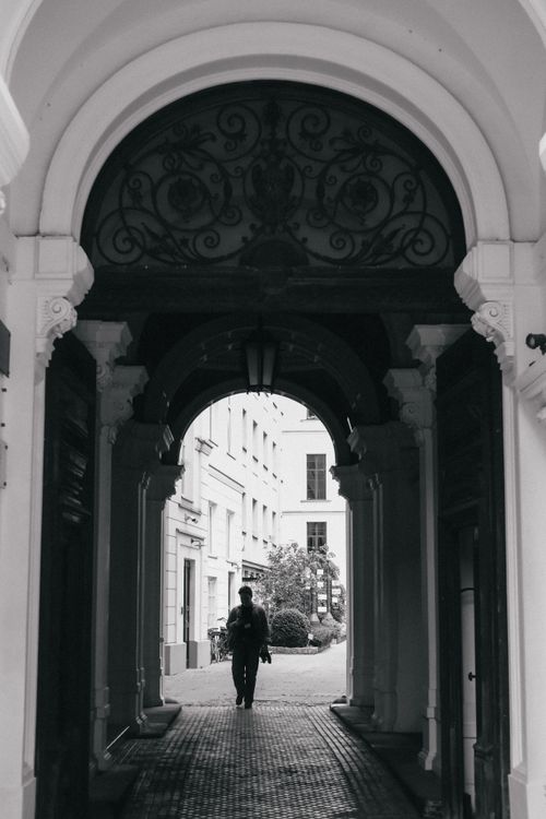 Free Black and white view through an ornate tunnel with a silhouetted walker in Warsaw. Stock Photo
