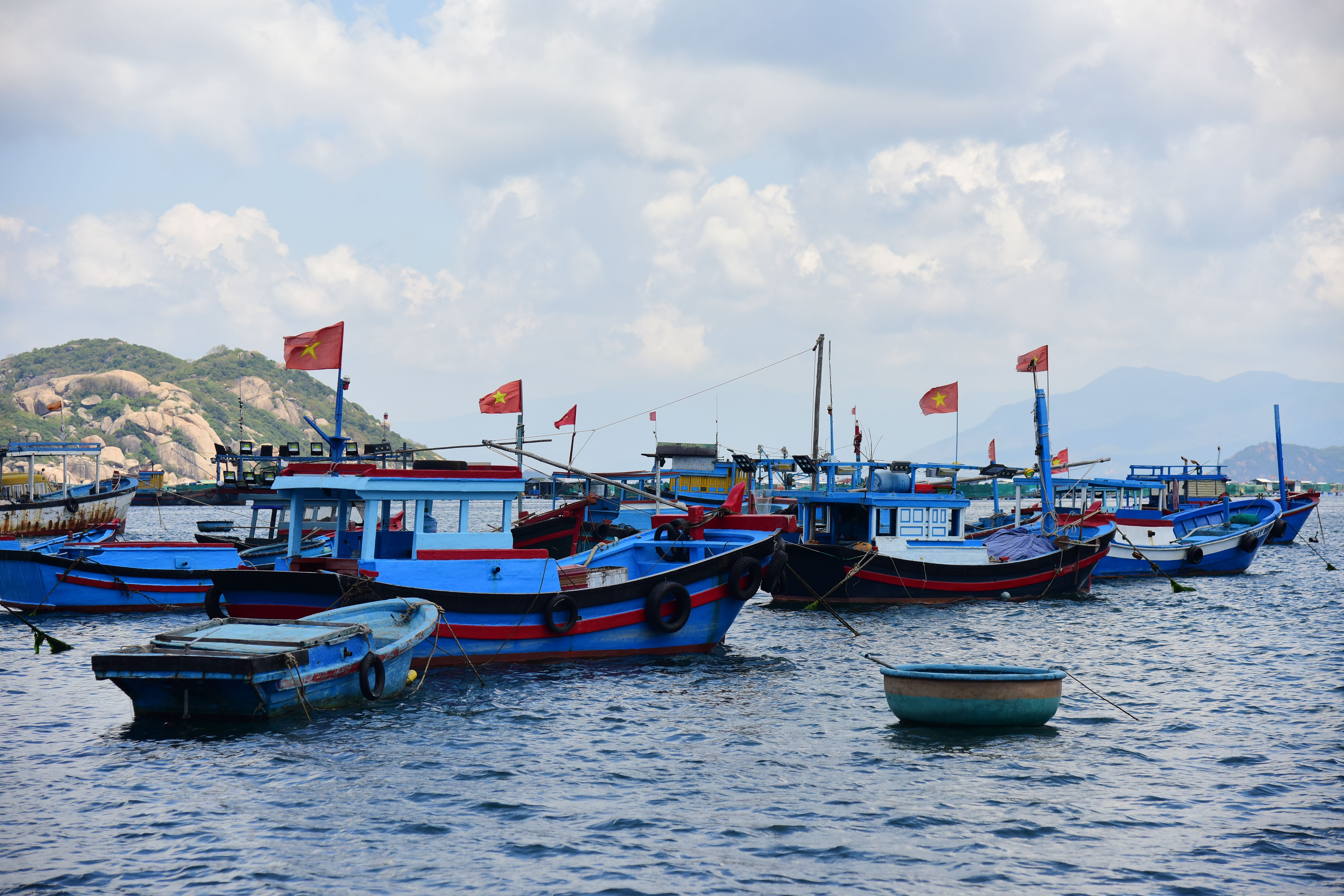 Vibrant fishing boats with flags docked in Nha Trang harbor on a clear day, capturing the essence of Vietnamese culture.