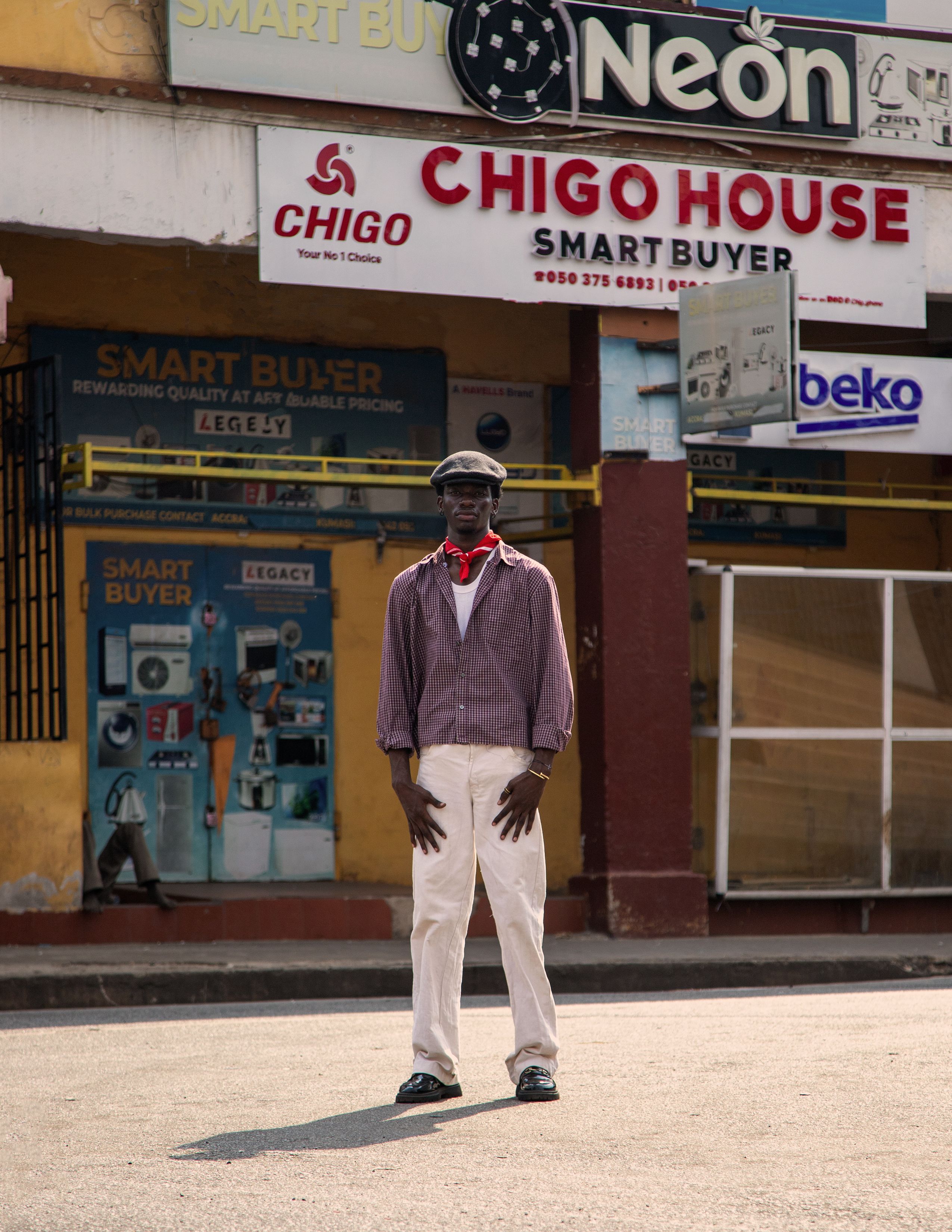 Man standing on city street in front of African store under sunlight.
