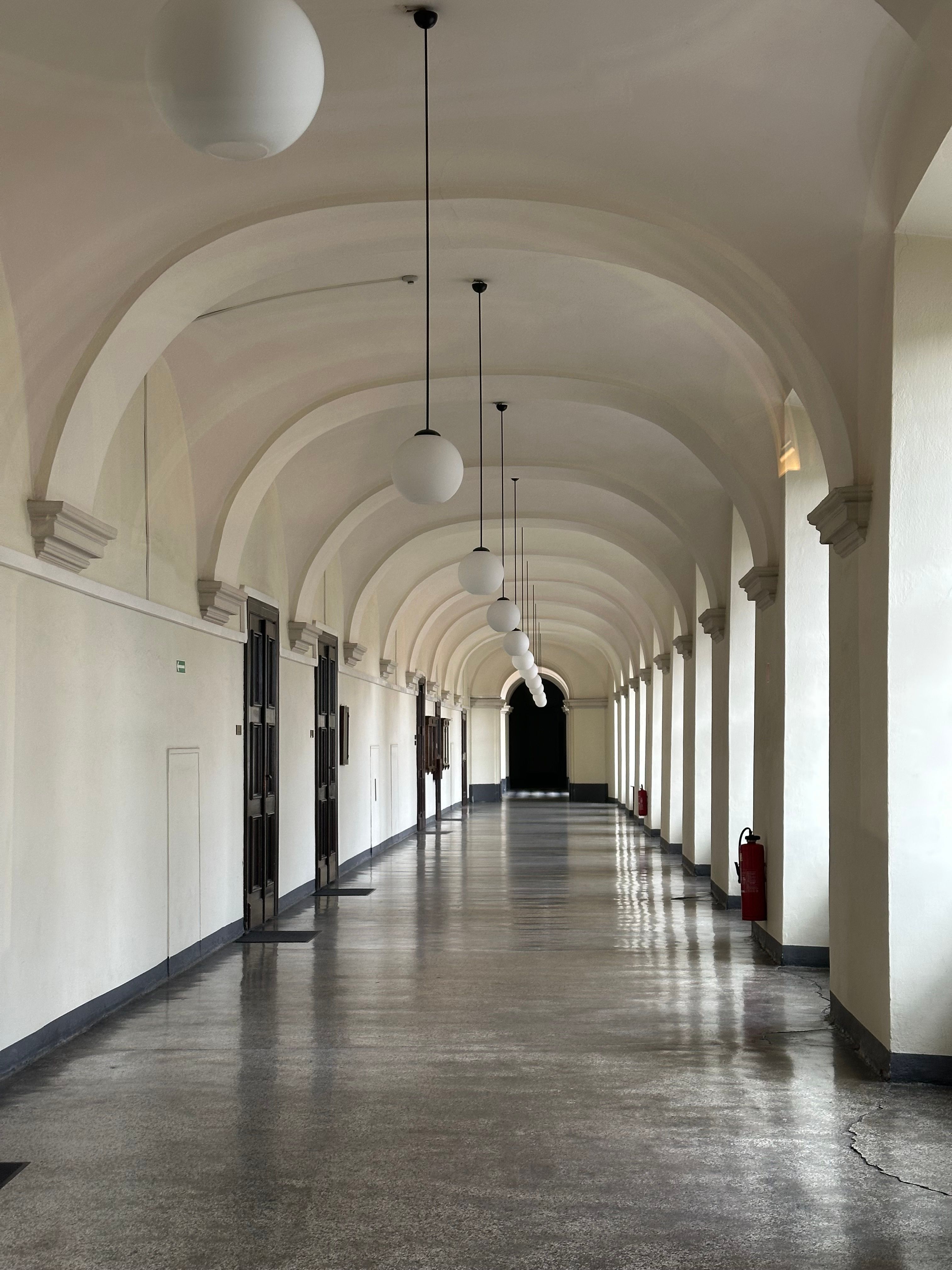 A long, elegant hallway with classic arches and vintage hanging lights, creating a serene atmosphere.
