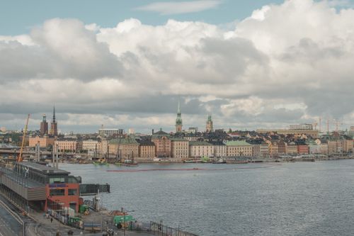 Free Panoramic view of Stockholm's waterfront with historic architecture under dramatic clouds. Stock Photo