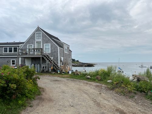 Free Gray shingle cottage by the ocean with fishing boats in Maine on a cloudy day. Stock Photo