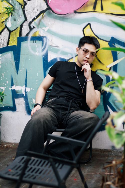 Free Casual portrait of a man sitting in front of vibrant street art, exuding urban style. Stock Photo