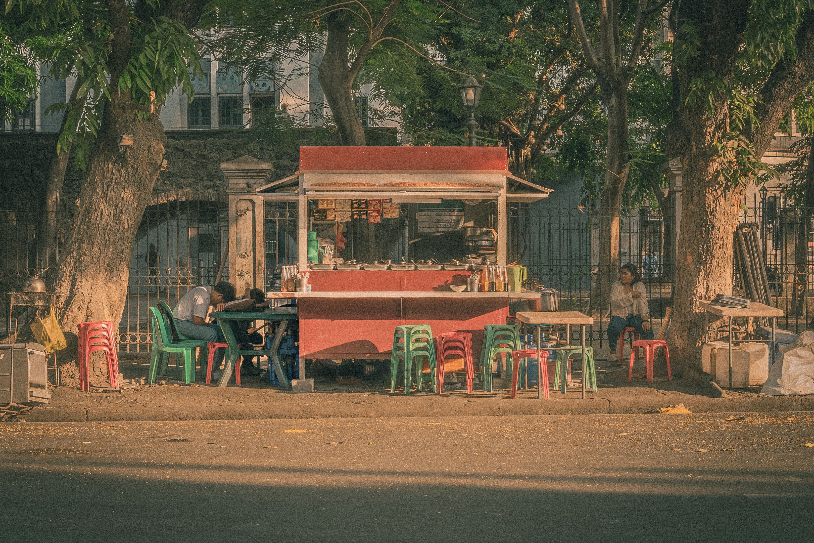 A rustic street food stall under trees in Manila, bustling with local flavor.