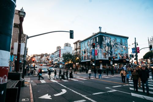 Free Vibrant intersection in San Francisco with people and traffic at dusk near iconic buildings. Stock Photo